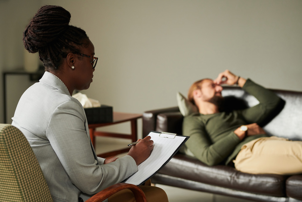 Psychologist making notes in card during her work with patient